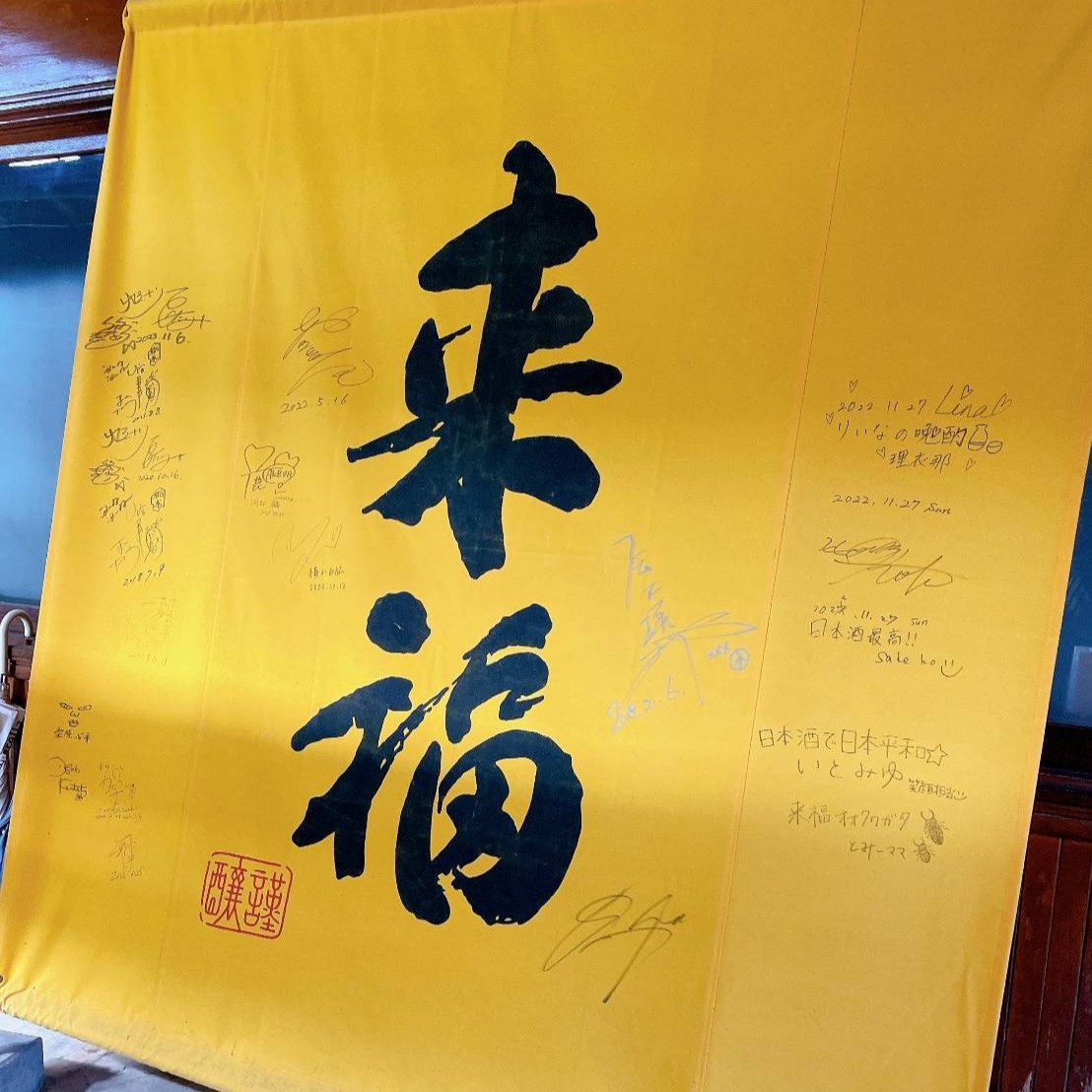 蔵に掲げられた、来訪者のサインが並ぶ黄色い大きな「来福」の布