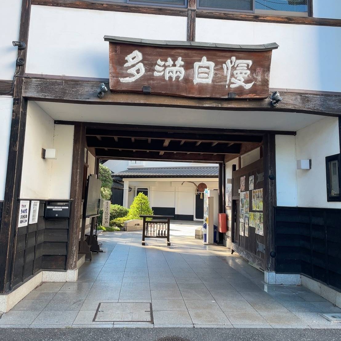 「多満自慢」の大きな木の看板が掛かる、白壁の蔵の門